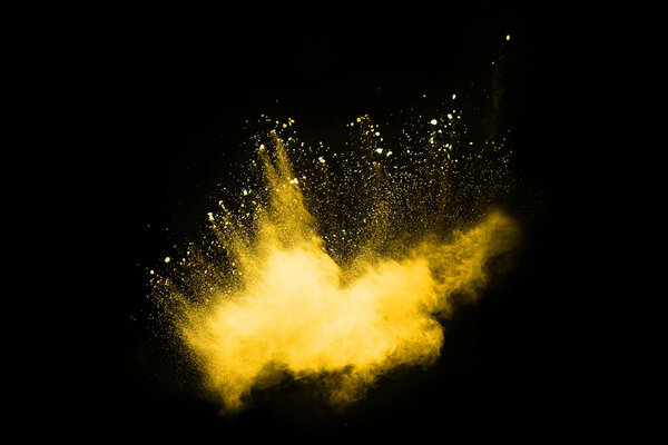 Freeze motion of yellow dust explosion isolated on black background.