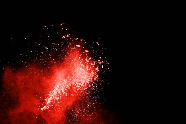 Siyah arka planda soyut kırmızı toz patlaması. Siyah arka planda soyut kırmızı toz sıçramış. Patlayan kırmızı barutun hareketsiz hareketi.