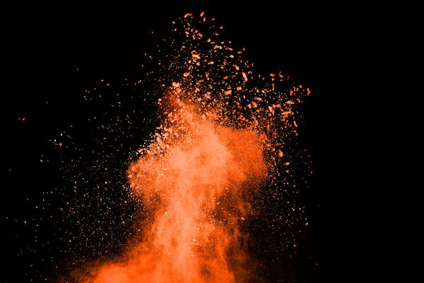 Freeze motion of Orange powder exploding, isolated on black background. Abstract design of red dust cloud.