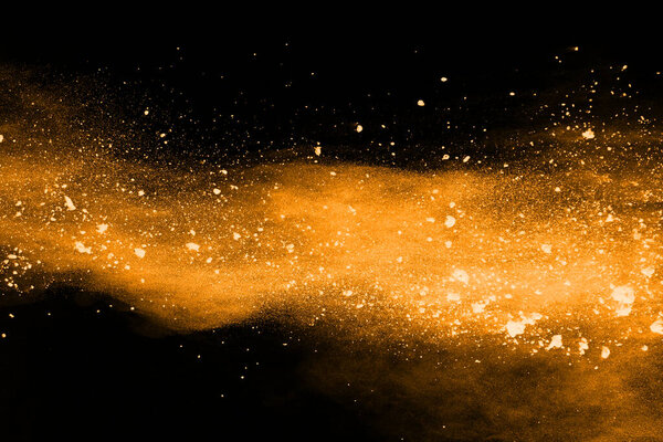 Freeze motion of yellow dust explosion isolated on black background.