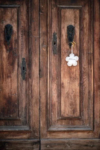 Old wooden monumental door with welcome sign