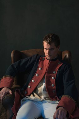 İmparatorluk tarzı sandalyede oturan adam.