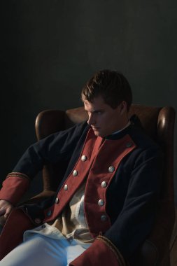 Sandalye bir kenara seyir içinde oturan tarihsel regency adam.