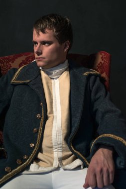 Tarihsel biedermeier adam kırmızı koltuğa oturur.