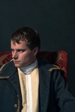 Tarihsel biedermeier adam kırmızı koltuğa oturur.