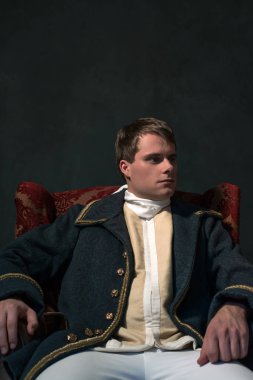 Tarihsel biedermeier adam kırmızı koltuğa oturur.
