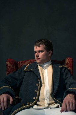 Tarihsel biedermeier adam kırmızı koltuğa oturur.