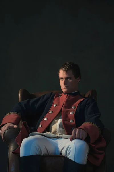 Man in empire style sitting in chair.
