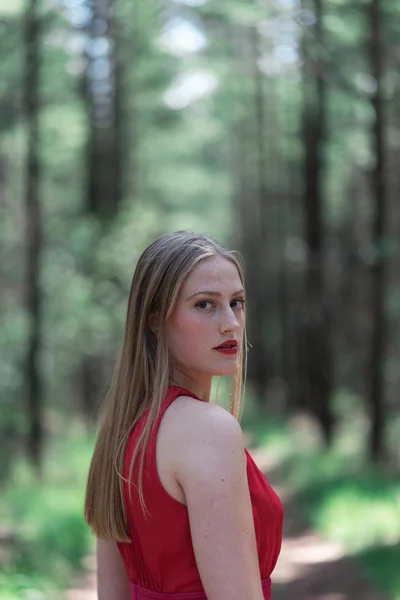 Blond Žena Červené Barvě Lese Při Pohledu Přes Rameno — Stock fotografie