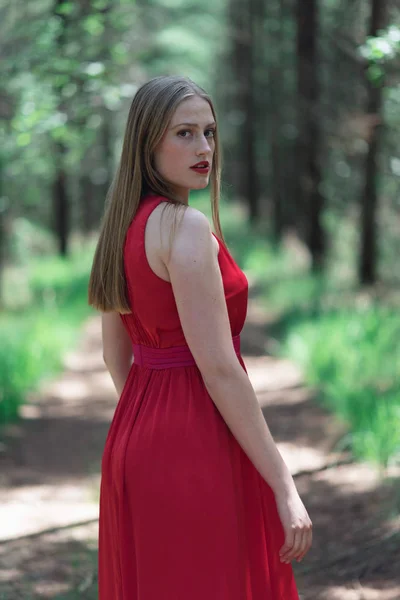 Femme Blonde Robe Rouge Forêt Regardant Par Dessus Épaule — Photo