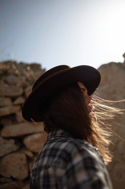 Esmer kadın kahverengi şapka ve güneş ışığı altında açık mavi Kareli gömlek.