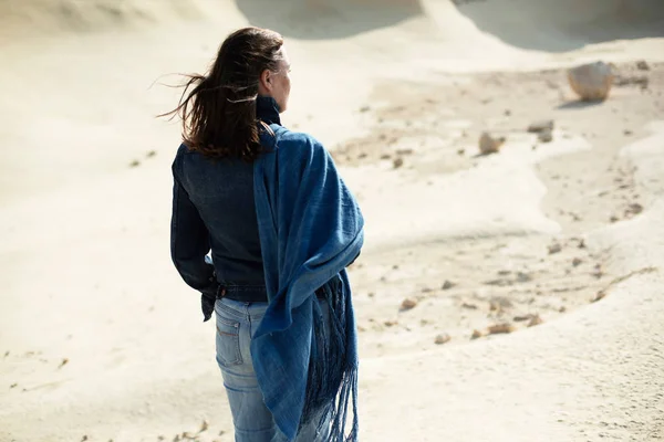 黑发妇女在蓝色布站立在荒凉的风的风景 后视图 — 图库照片