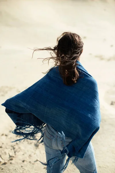 黑发妇女在蓝色布站立在荒凉的风的风景 后视图 — 图库照片