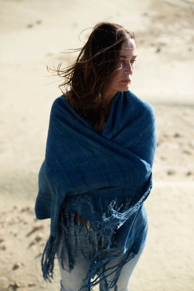 Брюнетка в голубой ткани, стоящая в пустынном ветреном пейзаже
.