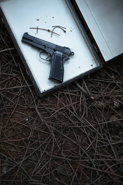 松树林公文包里的黑手枪 — 图库照片