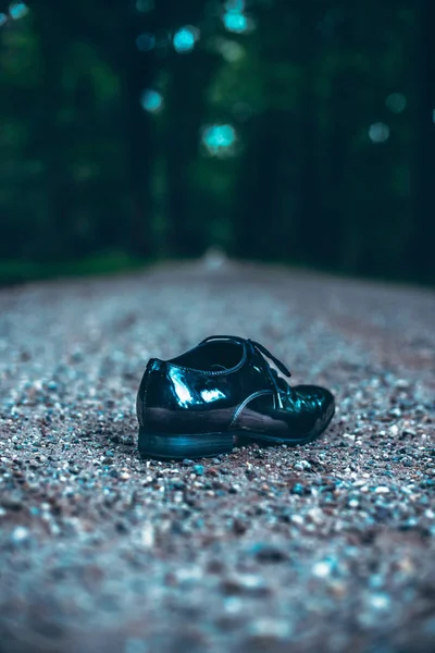 Lost shoe on road in dark forest.