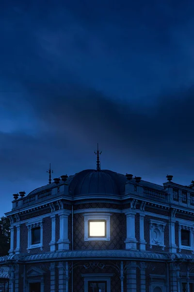 历史豪宅与被照亮的窗口在黑暗的天空之下在黄昏 — 图库照片