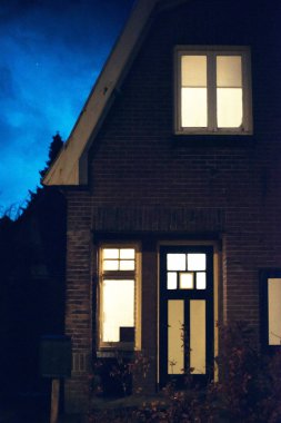Işıklı windows ve ön kapı evin alacakaranlıkta.