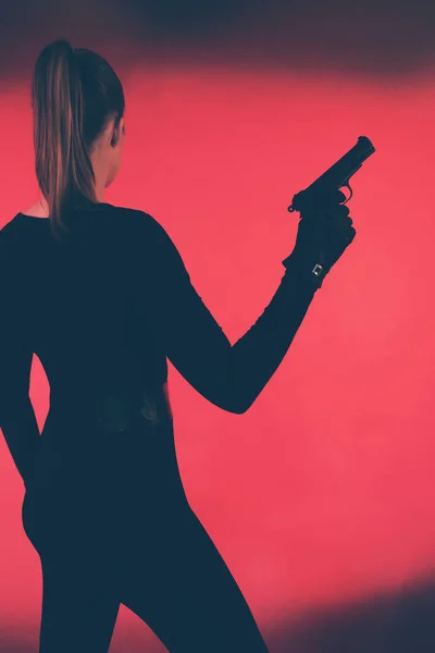 Γυναίκα με πυροβόλο όπλο ενάντια σε φόντο κόκκινο. — Φωτογραφία Αρχείου