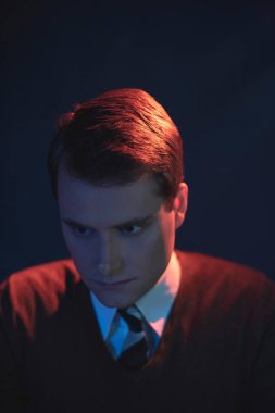 Kravat ve kahverengi kazak ciddi bir adam. Kırmızı ve mavi ışık ile yaktı.