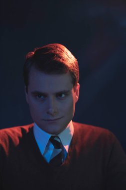 Korkunç gülümseyen adam kravat ve kahverengi süveter. Kırmızı ve mavi tarafından yaktı 