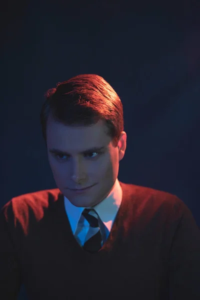 Homem sorrindo assustador de gravata e camisola marrom. Lit por vermelho e azul — Fotografia de Stock