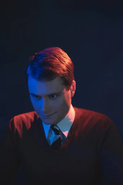 Homem sorrindo assustador de gravata e camisola marrom. Lit por vermelho e azul — Fotografia de Stock