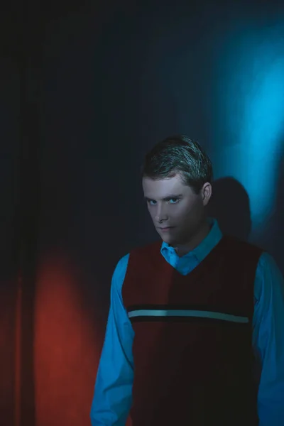 Homme en chemise et spencer rouge en lumière bleue et rouge debout par w — Photo
