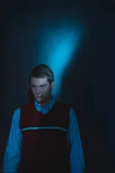 Man in het shirt en rode spencer in blauw en rood licht staande door w — Stockfoto