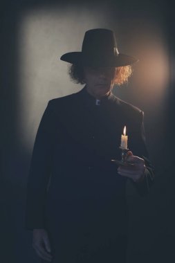 Siyah ceket ve şapka tutan mum gizemli Victorian rahip