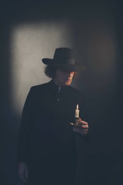 Siyah ceket ve şapka tutan mum gizemli Victorian rahip