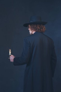 Siyah ceket ve şapka tutan gizemli adam mum. Arka v