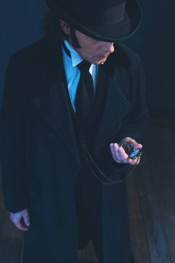 Uzun siyah ceket ve şapka tutan Edwardian adam cep İzle.