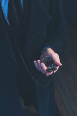 Edwardian man in long black coat holding pocket watch. clipart