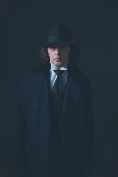 Mysterious victorian man in black coat and hat.