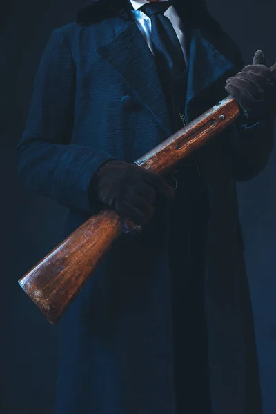 Homem de casaco preto comprido segurando rifle . — Fotografia de Stock