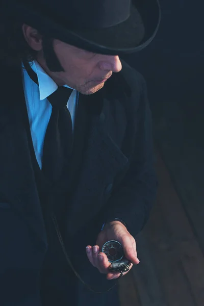 Edwardian man in lange zwarte jas en hoed Holding Pocket Watch. — Stockfoto