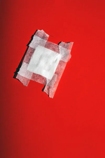 Bandage gauze with tape fallen on red floor. Top view. — Stock Photo, Image