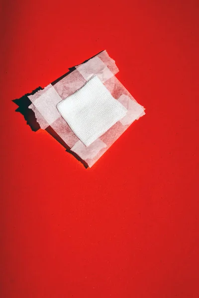 Bandage gauze with tape fallen on red floor. Top view. — Stock Photo, Image