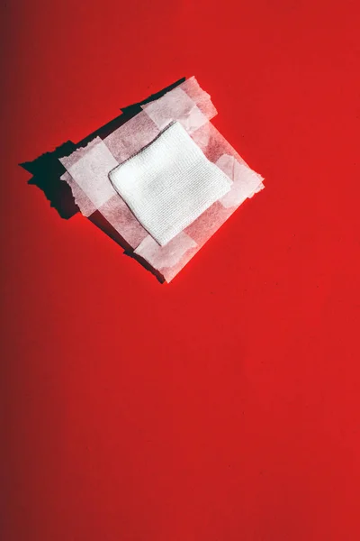 带胶带的绷带纱布落在红色的地板上。顶部视图. — 图库照片