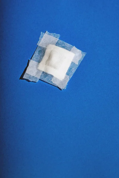 파란색 바닥에 테이프가 떨어지는 붕대. 맨 위 보기. — 스톡 사진