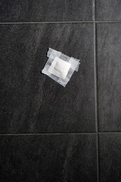 Bandage gauze with tape on grey tile floor. Top view. — Stock Photo, Image