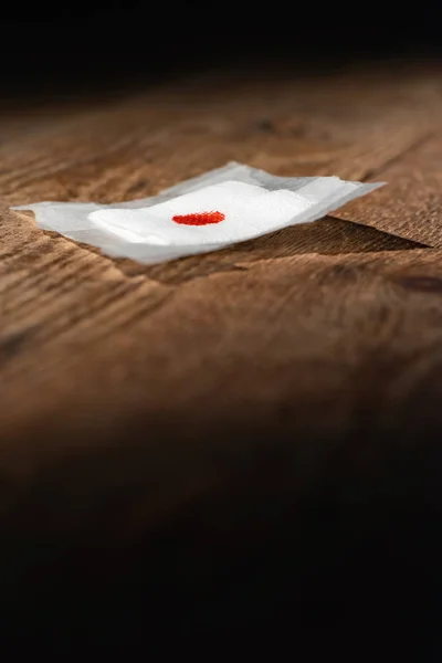 Benda usata con macchia di sangue caduta sul pavimento in legno . — Foto Stock