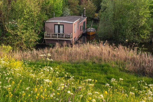 Hausboot im Frühling zwischen Büschen versteckt. — Stockfoto