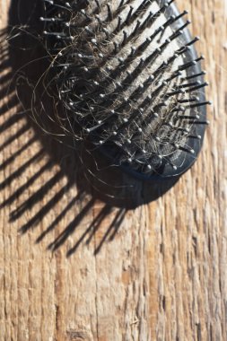 Ahşap zemin üzerinde sarı saçlı siyah saç fırçası.