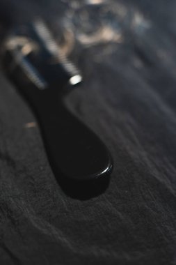 Koyu kumaş üzerinde kıvırcık sarı saçlı siyah tarak.