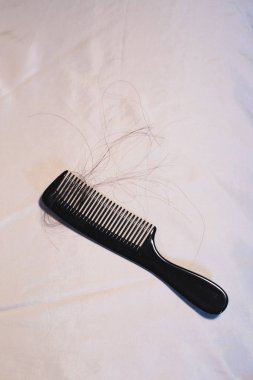 Parlak kumaş üzerinde kahverengi saçlı siyah tarak.