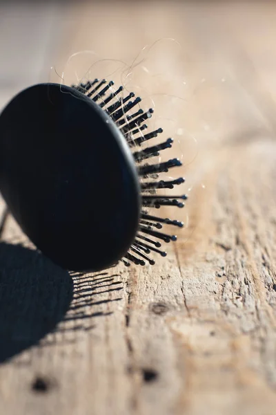 Spazzola nera con capelli biondi sul pavimento in legno . — Foto Stock