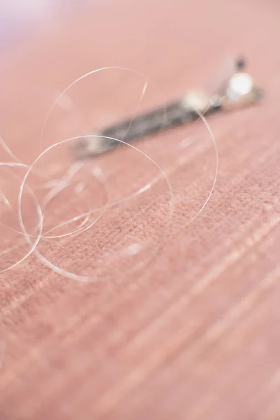 Hair clip with loose hair lying on pink sofa. — Stock Photo, Image