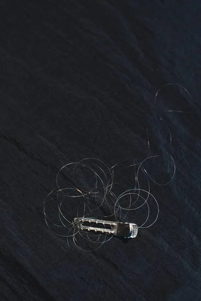 Hair clip with loose hair lying on black fabric. — Stock Photo, Image